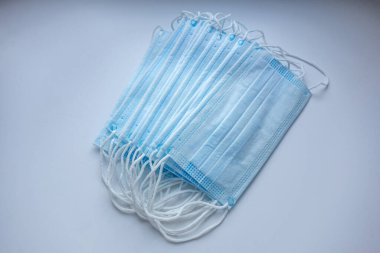 Beyaz arka planda elastik bantlı bir yığın mavi tıbbi maske.