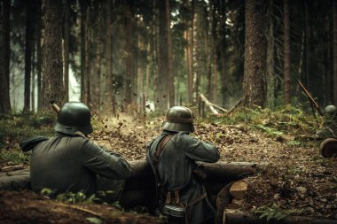 İkinci Dünya Savaşı 'nın Fin askerleri ellerinde silahla miğferleriyle ormandaki tahta siperlerde düşmandan ateş ediyorlar..