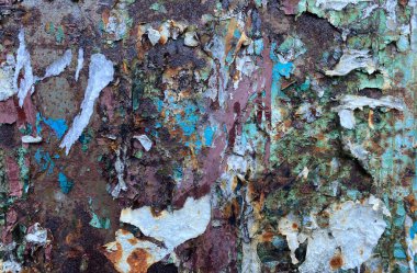 Paslı metal bir duvar yüzeyinin dokusu. İçinde boya kalıntıları ve reklamlardan artakalanlar var.