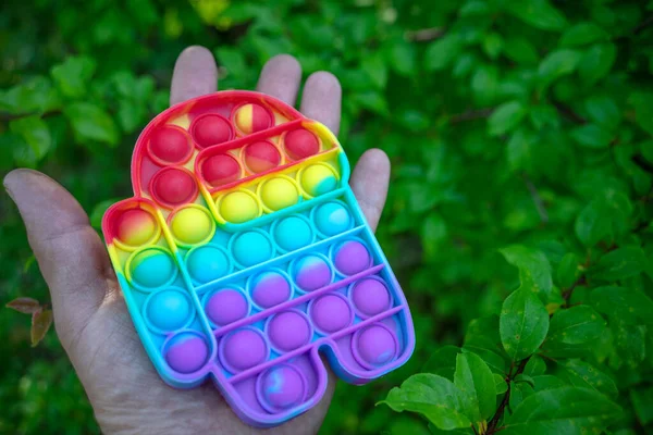 El, gökkuşağı renginde bir Popit anti-stres oyuncağını erkek şeklinde tutar.
