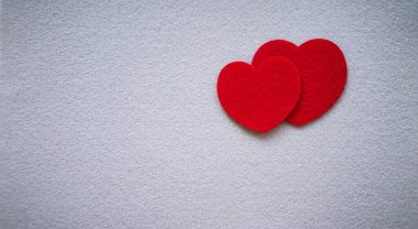 Gri bir izolasyonda tekstil malzemesinden yapılmış iki kırmızı kalp. Yazıt için temiz bir yer..