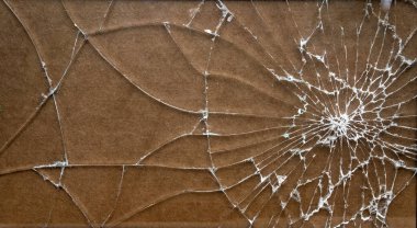 Kırık şeffaf cam, kahverengi izolasyonda beyaz çatlaklar var.
