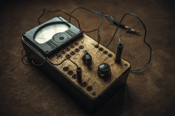 Old electrical appliance for checking and measuring the current level with wires and toggle switches on a wooden table in a retro style