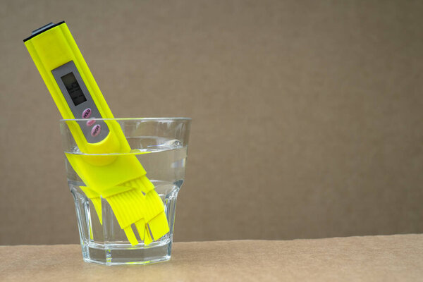 Тестер качества питьевой воды опускается в стакан водопроводной воды. Проверка чистоты воды в домашних условиях.