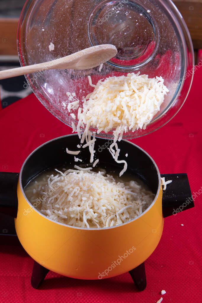 Preparación del queso suizo que se vierte en aceite para fondue para mojar el pan 2022