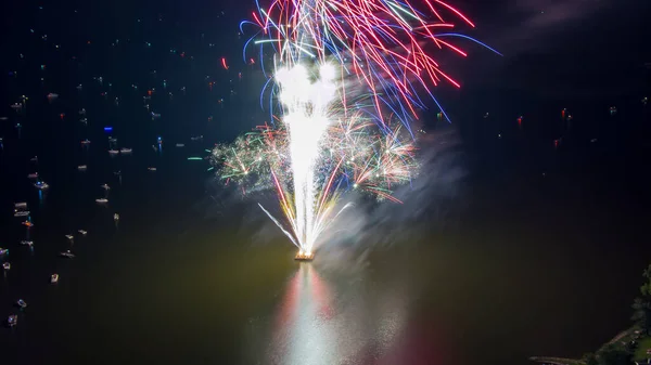 Fireworks on the forth of July fired from a barge on a lake taken with a drone.