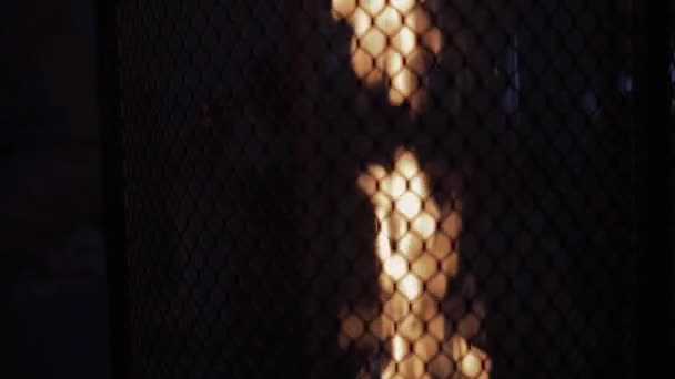 Slow-motion shooting of a flamame behind a metal grate on a black background. — Stock video