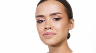 Güzel makyajlı tatlı esmer beyaz arka planda kameraya gülümsüyor..