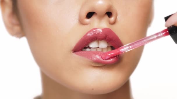 Primer plano de la mitad inferior de la cara de una mujer sobre un fondo blanco durante el maquillaje de labios. — Vídeos de Stock