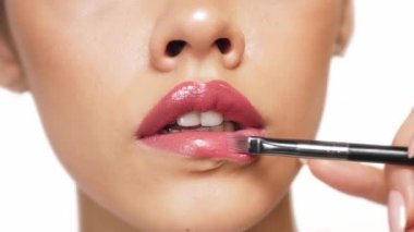 Dudak makyajı sırasında beyaz arka planda bir kadının yüzünün alt yarısı..