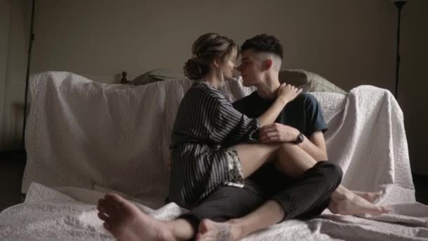 Joven hermosa pareja encantadora está teniendo un momento romántico. Sentado en el suelo junto a la cama abrazando y sonriendo — Vídeos de Stock