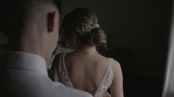 O noivo ajuda a vestir a noiva. Preparação dos recém-casados para o casamento. O casal veste as roupas de casamento. Manhã recém-casados no dia do casamento — Vídeo de Stock