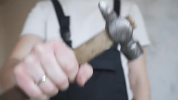 A young man in construction overalls demonstrates the hammer tool to the camera — Stock Video