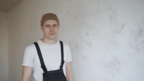 A man in overalls approaches the camera and crosses his arms over his chest — Stock Video