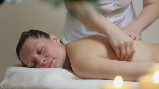 Een mooi brunette meisje ligt op een rug massage procedure in de spa. — Stockvideo