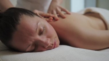 Güzel esmer kadın güzellik salonunun parlak ofisinde sırt masajı yaptırıyor.