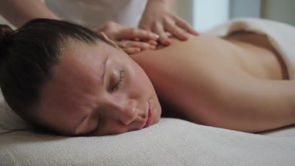 Mujer morena bonita recibe un masaje de espalda en la oficina luminosa del salón de spa — Vídeos de Stock