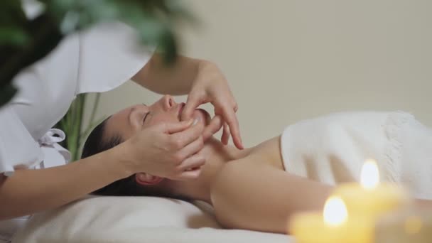 Belle femme brune dans un salon de spa sur massage avec des pierres de gouache. — Video