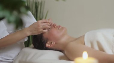 Şakak bölgesinin guaj taşlarıyla masaj yapan tatlı esmer..