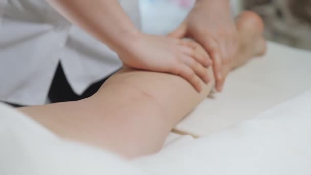 Dans le bureau lumineux du salon de spa, une femme brune reçoit un massage des pieds — Video