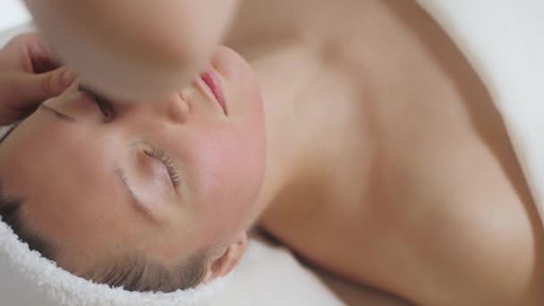 Leuke brunette vrouw op gezicht massage in spa salon. Wellness gezichtsmassage spa — Stockvideo