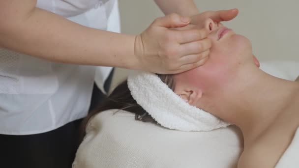 Słodka brunetka na masażu twarzy w salonie spa. Wellness masaż twarzy spa — Wideo stockowe