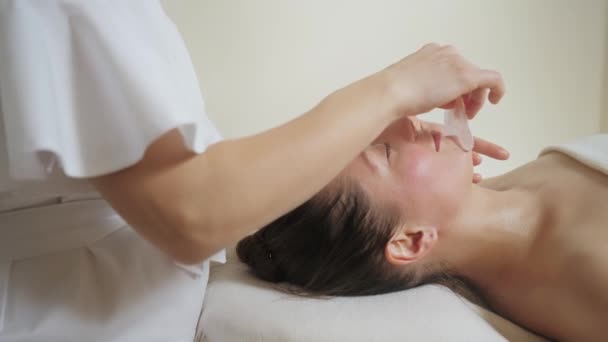 Belle femme brune dans un salon de spa sur massage avec des pierres de gouache. — Video