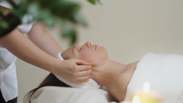 Söt brunett kvinna på ansiktsmassage i spa salong. Wellness ansikte massage spa — Stockvideo