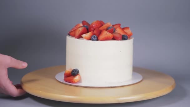 Presentatie van een prachtige witte taart versierd met aardbeien en bosbessen. — Stockvideo