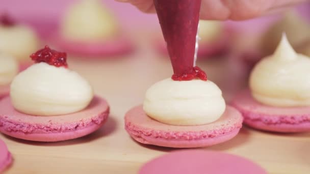 Beautiful pink macaroons fill with pink jam on a pink background. — Stock Video