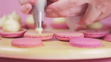 Pembe arka planda açık kremayla doldurulmuş güzel pembe badem kurabiyeleri..