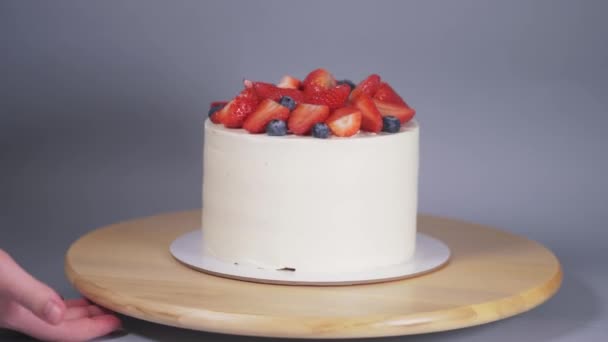 Presentatie van een prachtige witte taart versierd met aardbeien en bosbessen. — Stockvideo