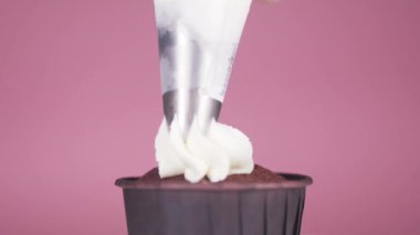 Koyu çikolatalı kekin üzerine beyaz krema sürüyorum..