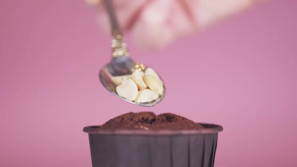 Primer plano sobre un fondo de rosa en una magdalena de chocolate con una cuchara, poner las nueces — Vídeos de Stock