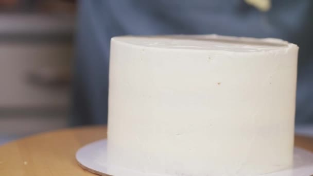 Жінка вирівнює легкий крем на торт на обертовій підставці на домашній кухні — стокове відео
