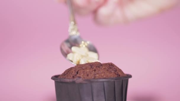 Крупный план на розовом фоне в шоколадный кекс с ложкой, положить орехи — стоковое видео