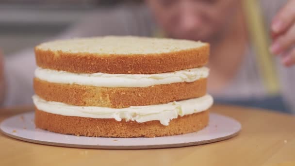 De banketbakker roteert de taart, onderzoekt deze in het kookproces. — Stockvideo