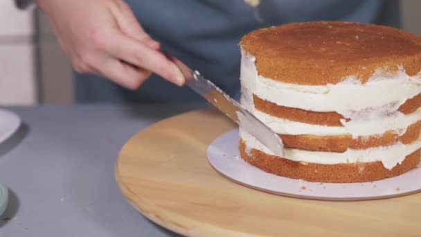 El chef de pastelería nivela el exceso de crema en el lado de la torta. Primer plano — Vídeos de Stock