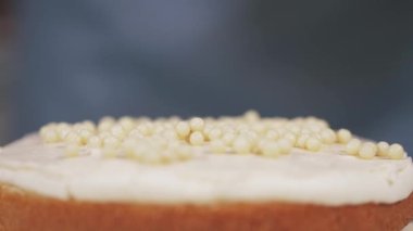 Pasta şefi pastanın kremasına beyaz çikolata topları ekler. Yakın plan.