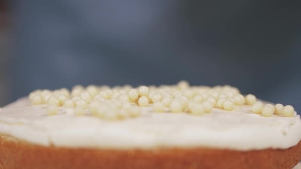 O chef de pastelaria adiciona bolas de chocolate branco ao creme do bolo. Close-up — Vídeo de Stock