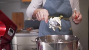 Pasta şefi kremalı peyniri gezegen mikserinin kasesine koyar.