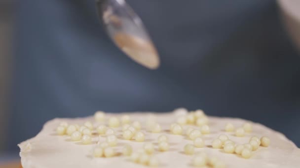 O chef de pastelaria adiciona bolas de chocolate branco ao creme do bolo. Close-up — Vídeo de Stock