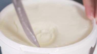 pastry chef opens a new package of cream cheese curd with a knife to make a cake