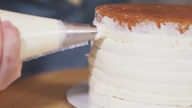 Pasta şefinin pastaya beyaz krema sürdüğü yakın plan..
