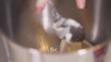 Pasta şefi kremalı peyniri gezegen mikserinin kasesine koyar.