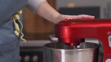 The pastry chef turns on the red planetary mixer. Close-up