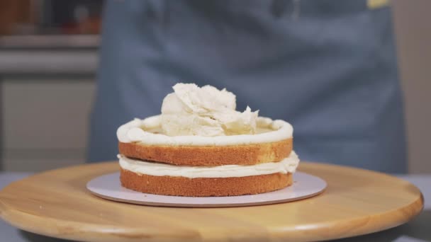 Het aanbrengen van de crème op de spons cake tijdens de assemblage van de taart. — Stockvideo