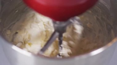 Kamera beyaz kremanın pasta için hazırlandığı bir kaseye bakıyor.