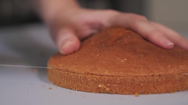 De banketbakker gebruikt een speciale snijder om de gebakken taart in gelijke lagen te snijden.. — Stockvideo