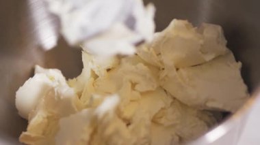 Pasta şefi kremalı peyniri gezegen mikserinin kasesine koyar.